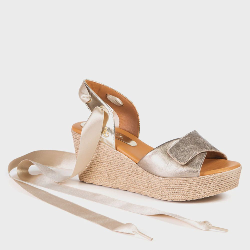 Angled front view of an espadrille sandal with a wedge heel.  Open toe and heel with an adjustable front strap.  Silky ribbon tie at the ankle.