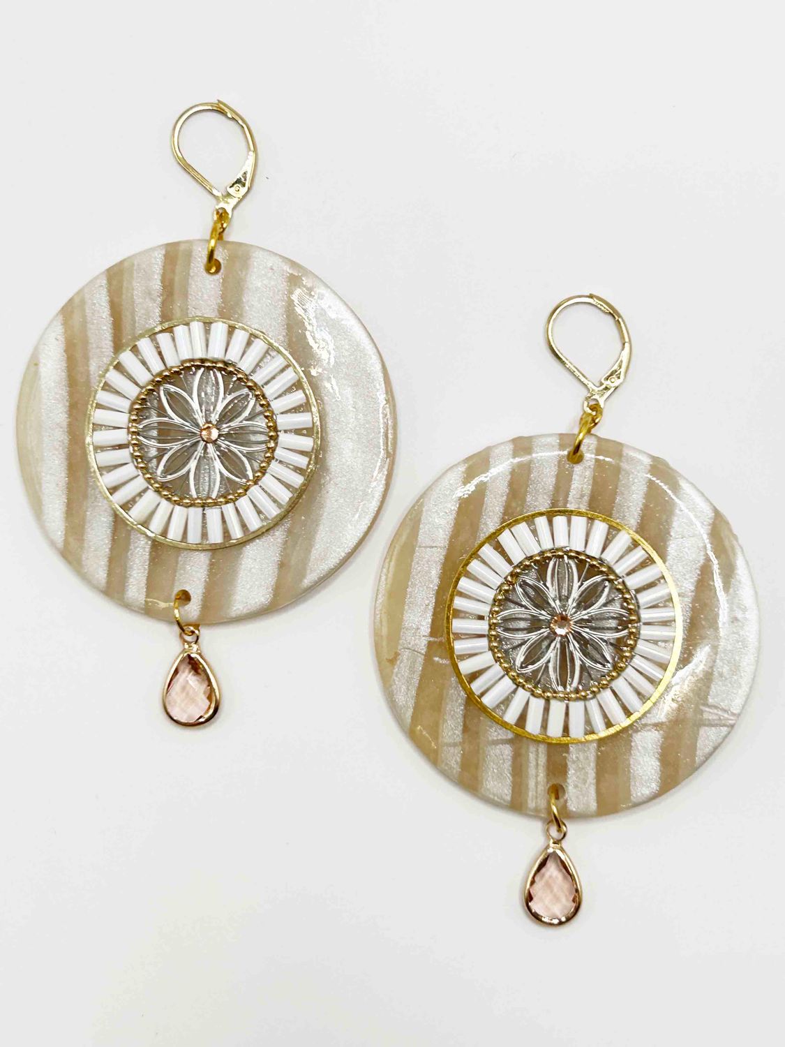 Oorbel aan hanger, parelmoer met witte en zachtroze accenten.