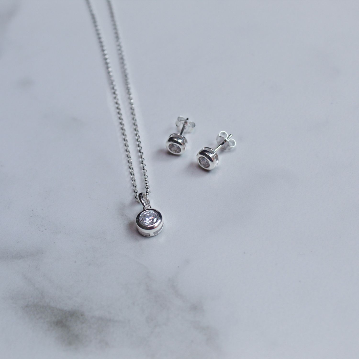 Juego de aretes y dije con zirconia blanca y marco bisel