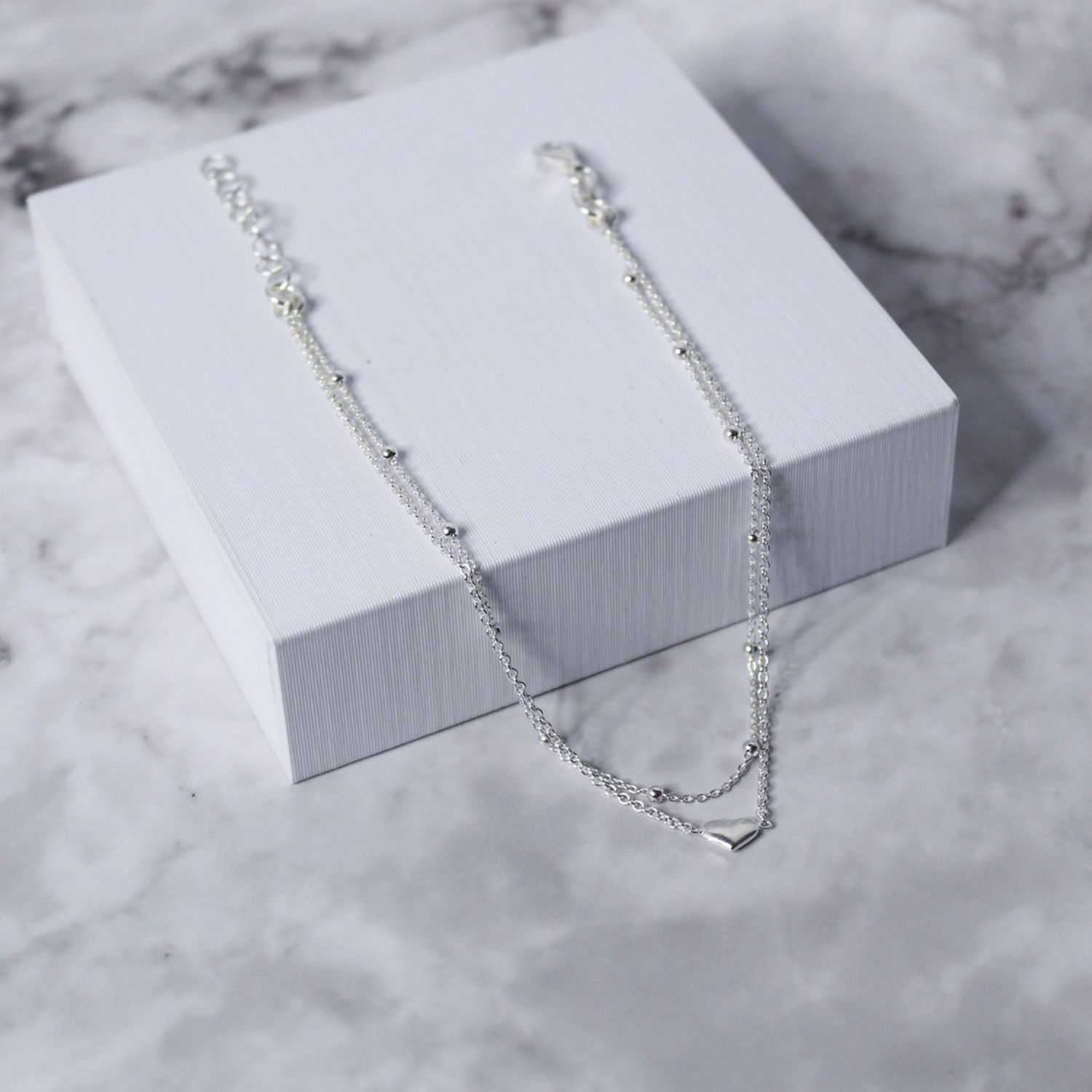 Tobillera doble cadena con detalle de bolitas y corazón