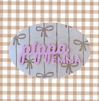 Timber wall sign with engraved bow pattern and custom names in pink acrylic – ideal for nursery or kids’ room decor.