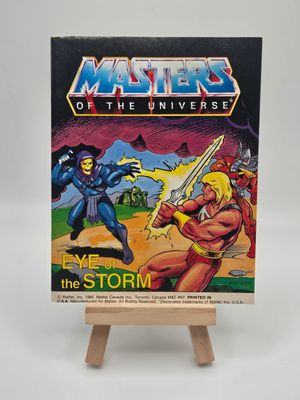 Front cover of the vintage &#39;Masters of the Universe&#39; mini comic &#39;Eye of the Storm&#39; displayed on a small wooden easel. The cover illustration shows Skeletor and He-Man fighting, set against a dramatic stormy backdrop.