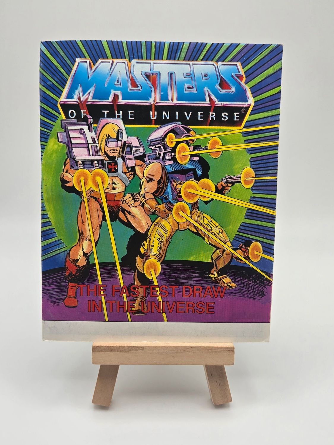 Front the English cover of a vintage &#39;Masters of the Universe&#39; mini comic titled &#39;The Fastest Draw in the Universe&#39;, featuring He-Man and allies equipped with advanced weaponry poised in dynamic action.