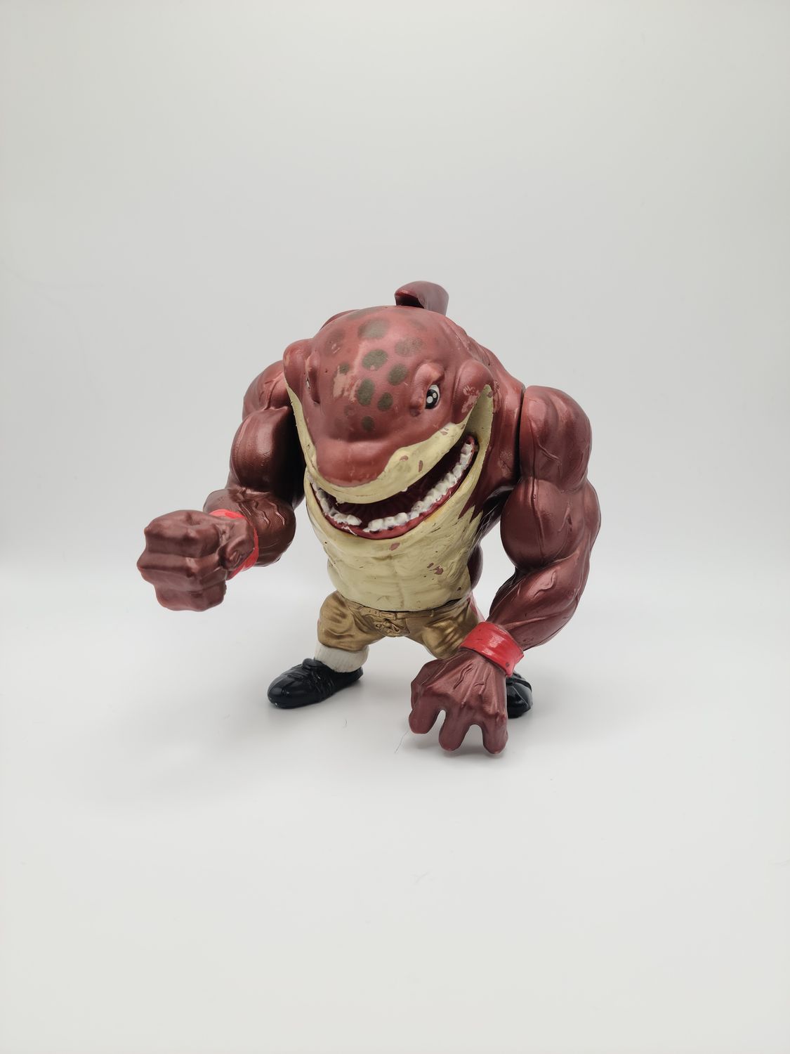 Front view of the 1994 Big Slammu (red sweat wrist bands) Street Sharks vintage action figure made by Mattel standing on a flat surface.
