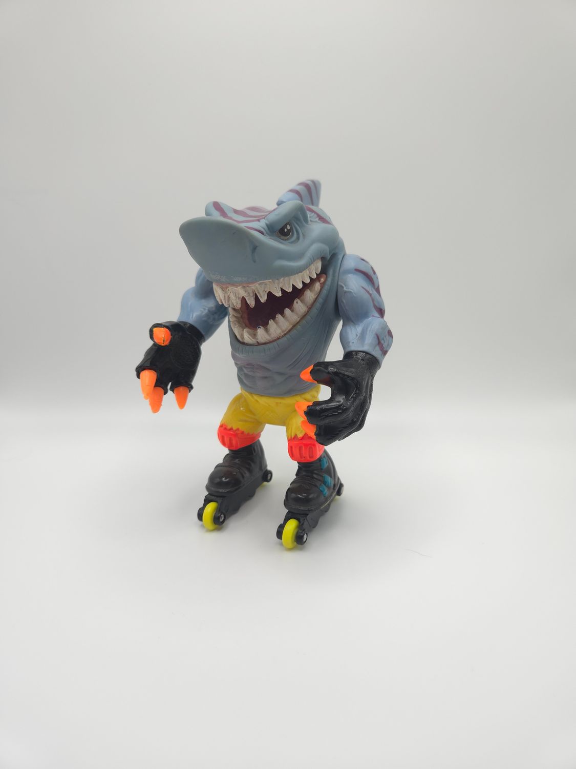 Front view of the figure, highlighting the fierce facial expression, sharp teeth, and orange claws.