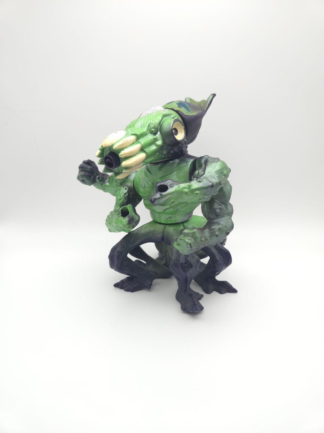 Frontal view of the Killamari action figure from the Street Sharks series, featuring a distinctive octopus design with large, yellow eyes, and green and purple skin. The figure is posed with arms raised, showing its menacing clawed hands.