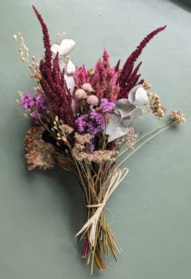 Small bouquet of pink and cream dried flowers, tied with twine, on a green table.