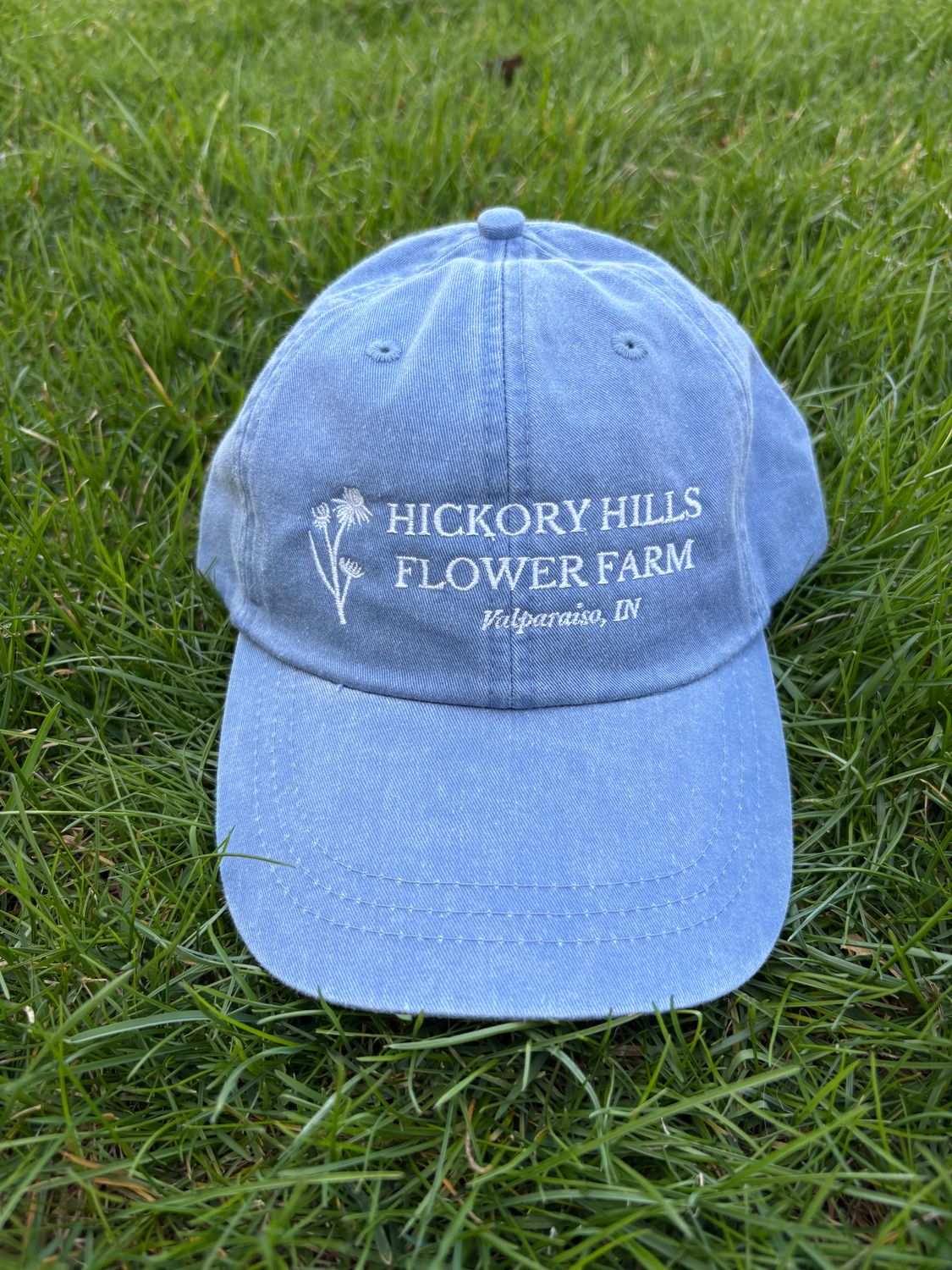Blue hat with white logo sitting on grass.
