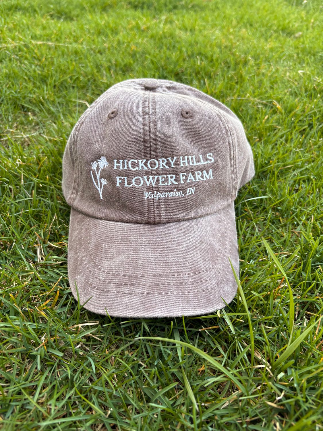Brown hat with logo, sitting in grass