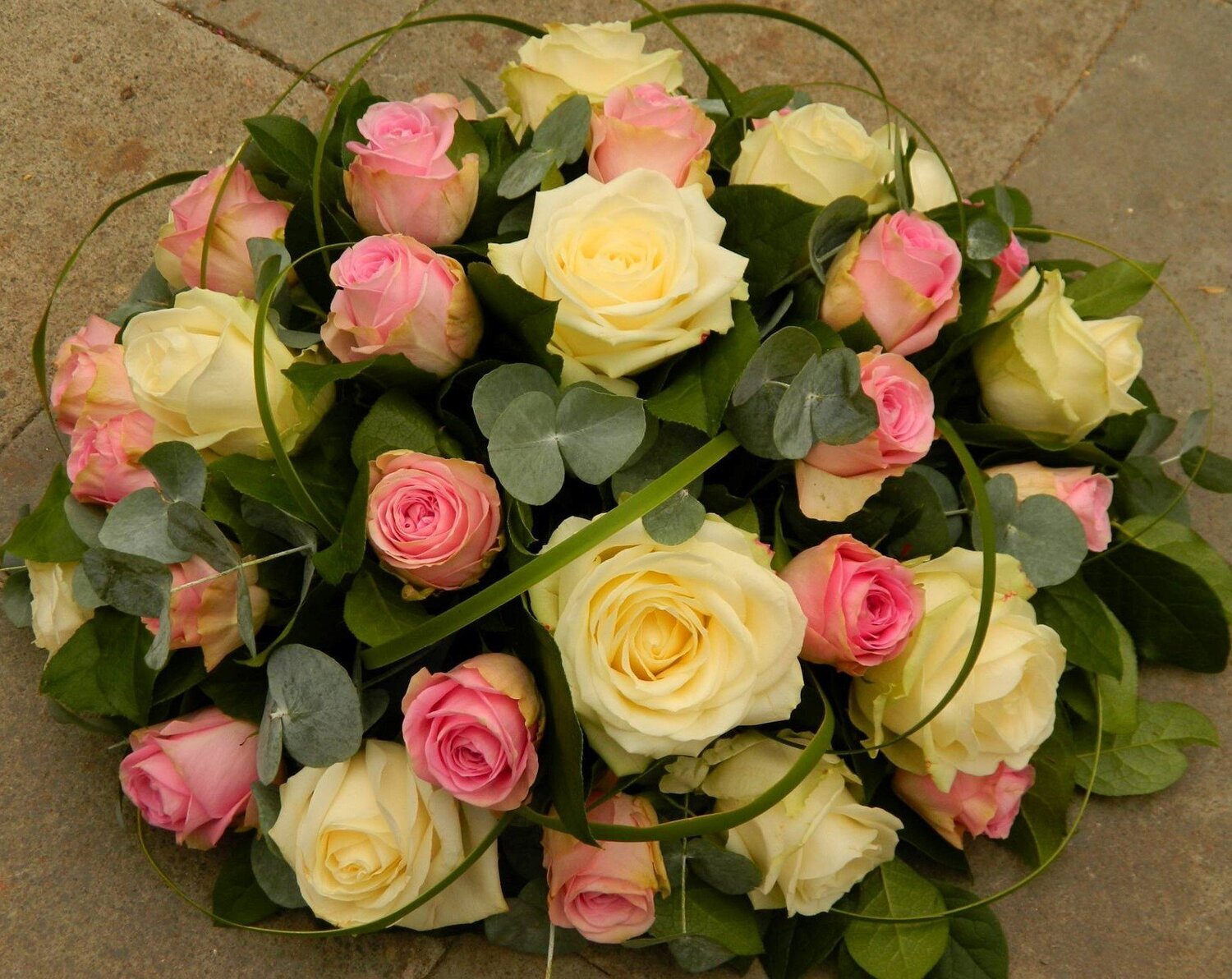 Rond bloemstuk met rozen in verschillende kleuren en groenvoorziening