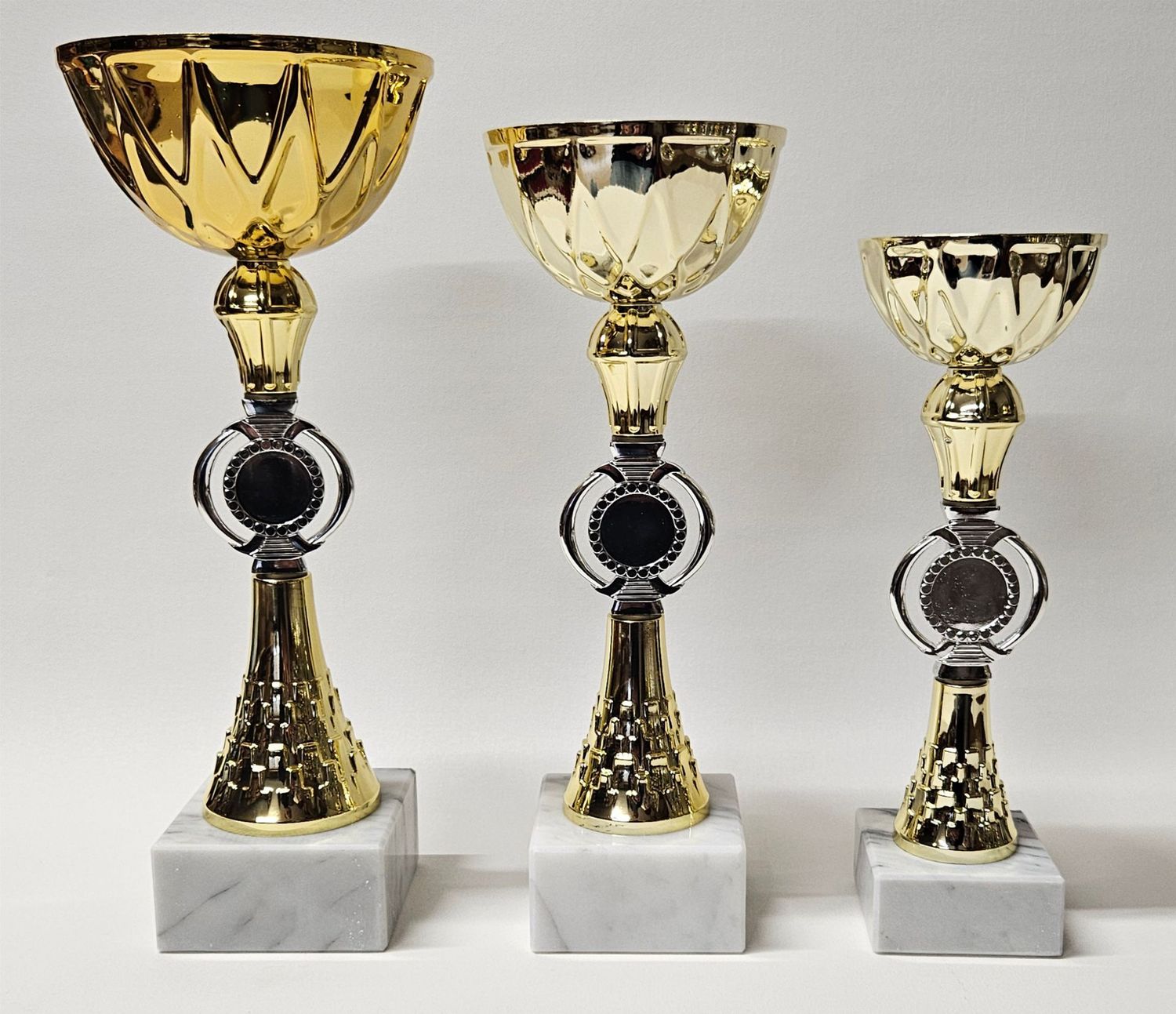 Drei Pokale der Serie ORPHEUS mit goldfarbener Schale, silber-goldenem Mittelteil mit Emblemhalter und Marmorsockel in unters