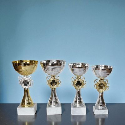 Vier Pokale Modell Emily mit silbernem und goldfarbenem Kelch, dekorativem Mittelteil und weißem Marmorsockel