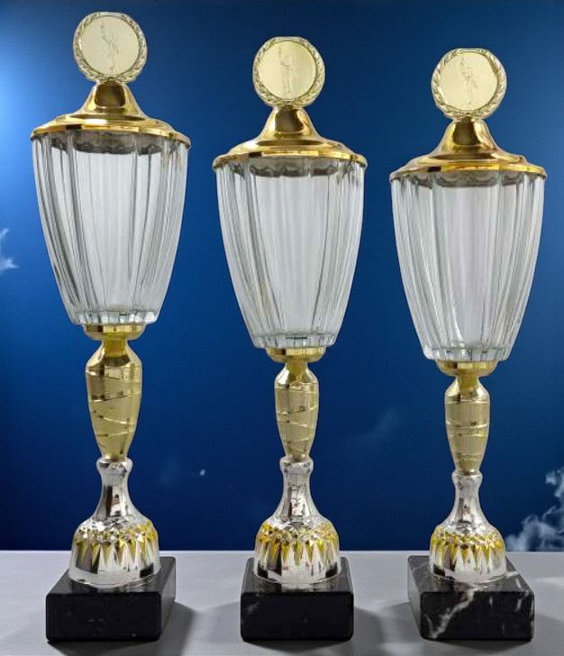 Glaspokal „Golling“ mit klarem Glas, goldfarbenem Deckel und Emblemträger auf schwarzem Marmorsockel.