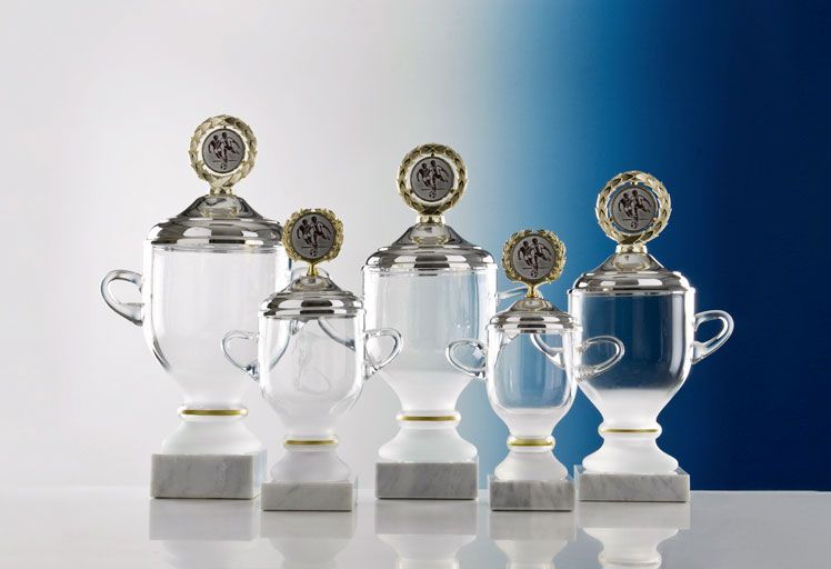 Glaspokal „Cremona“ mit klarem Glaskorpus, Goldrand, Deckel und Kranz auf weißem Marmorsockel.