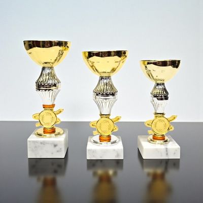 Pokal Hedwig mit glatter goldfarbener Schale, dekorativem Mittelteil, Emblemträger und weißem Marmorsockel, 3 Größen