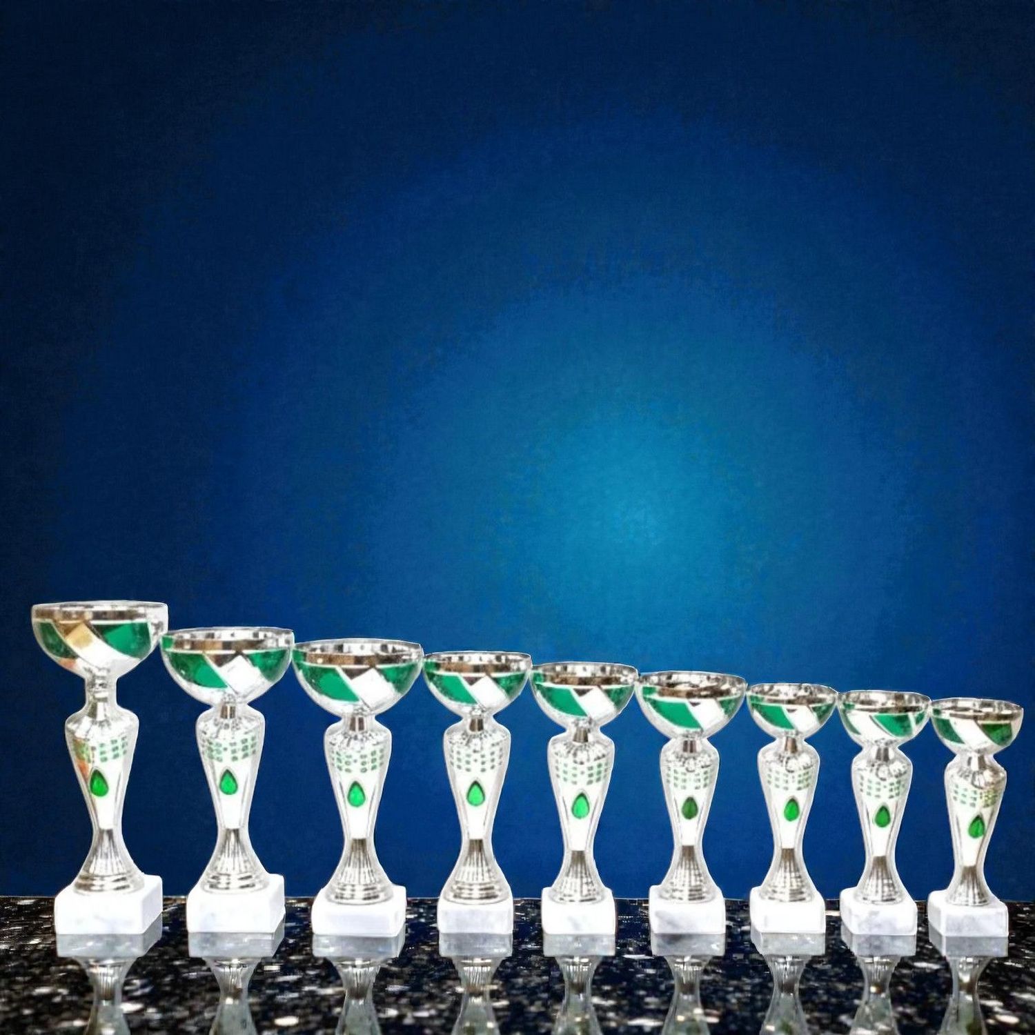 Pokal Pokal-Set Vigaun mit silberfarbenen Pokalen und grünen Akzenten, abgestufte Höhen auf hellen Sockeln vor blauem Hintergrund.