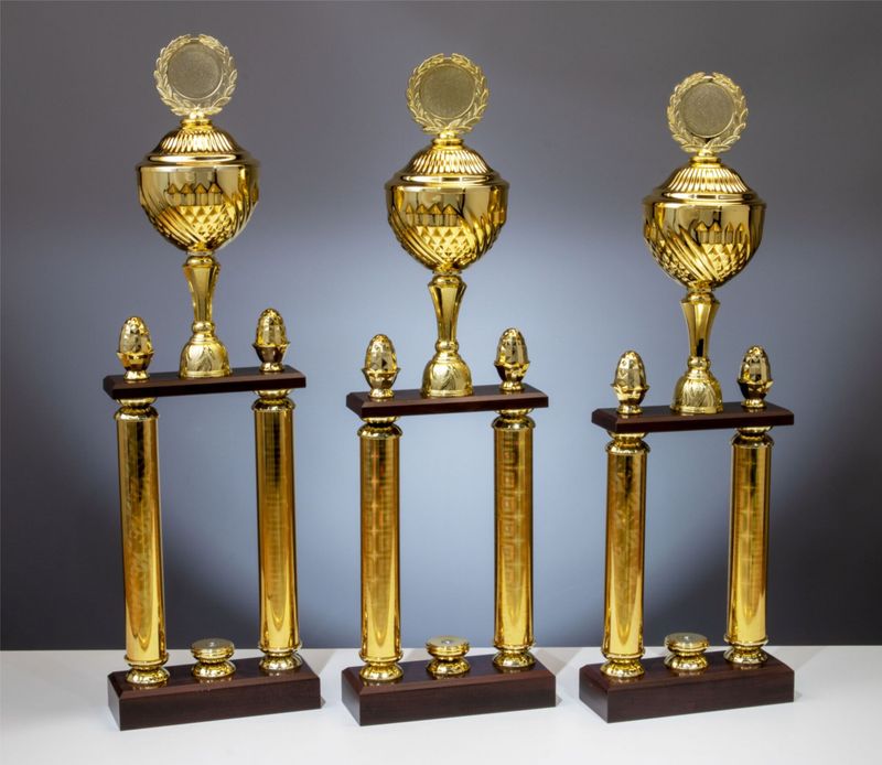 Säulenpokal Dakota in Goldoptik mit klassischem Kelch, goldfarbenen Säulen und Holzsockel, erweiterbar mit Figuren, 3 Größen