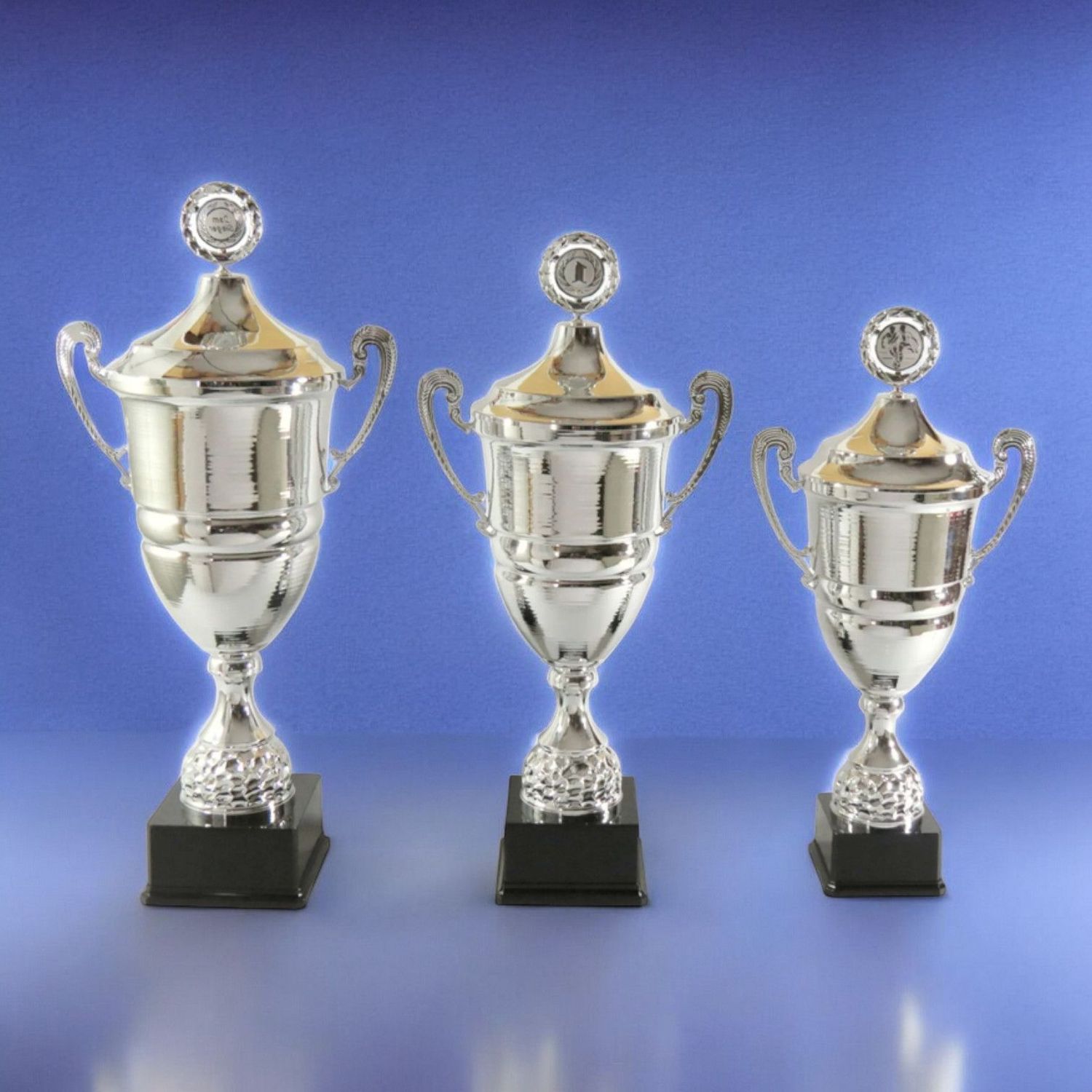 Wanderpokal-Serie „Champion“ in Silberoptik mit Deckel und Kranz, drei Größen auf schwarzem Kunststoffsockel