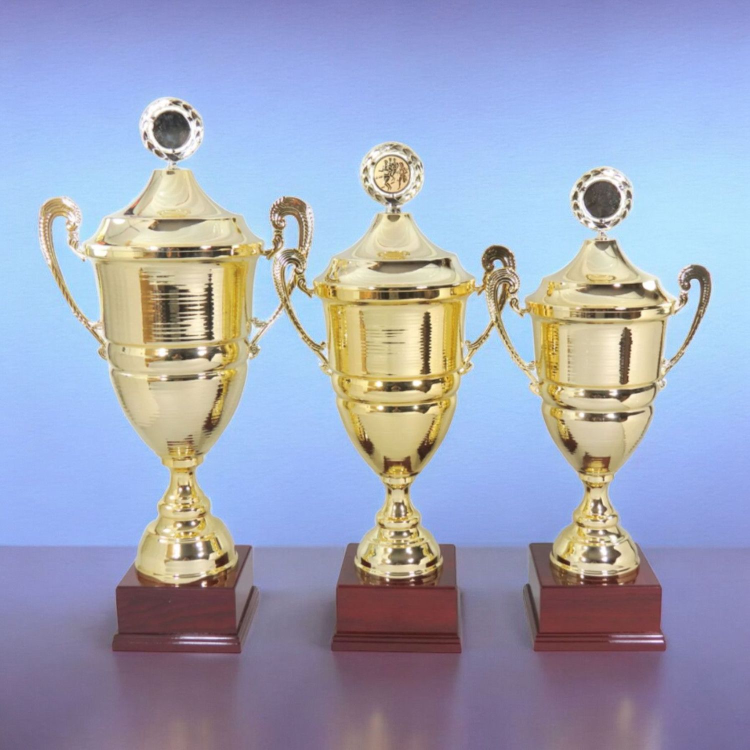 Wanderpokal-Serie „Europa“ in Goldoptik mit Deckel und Kranz, drei Größen auf dunklem Holzsockel