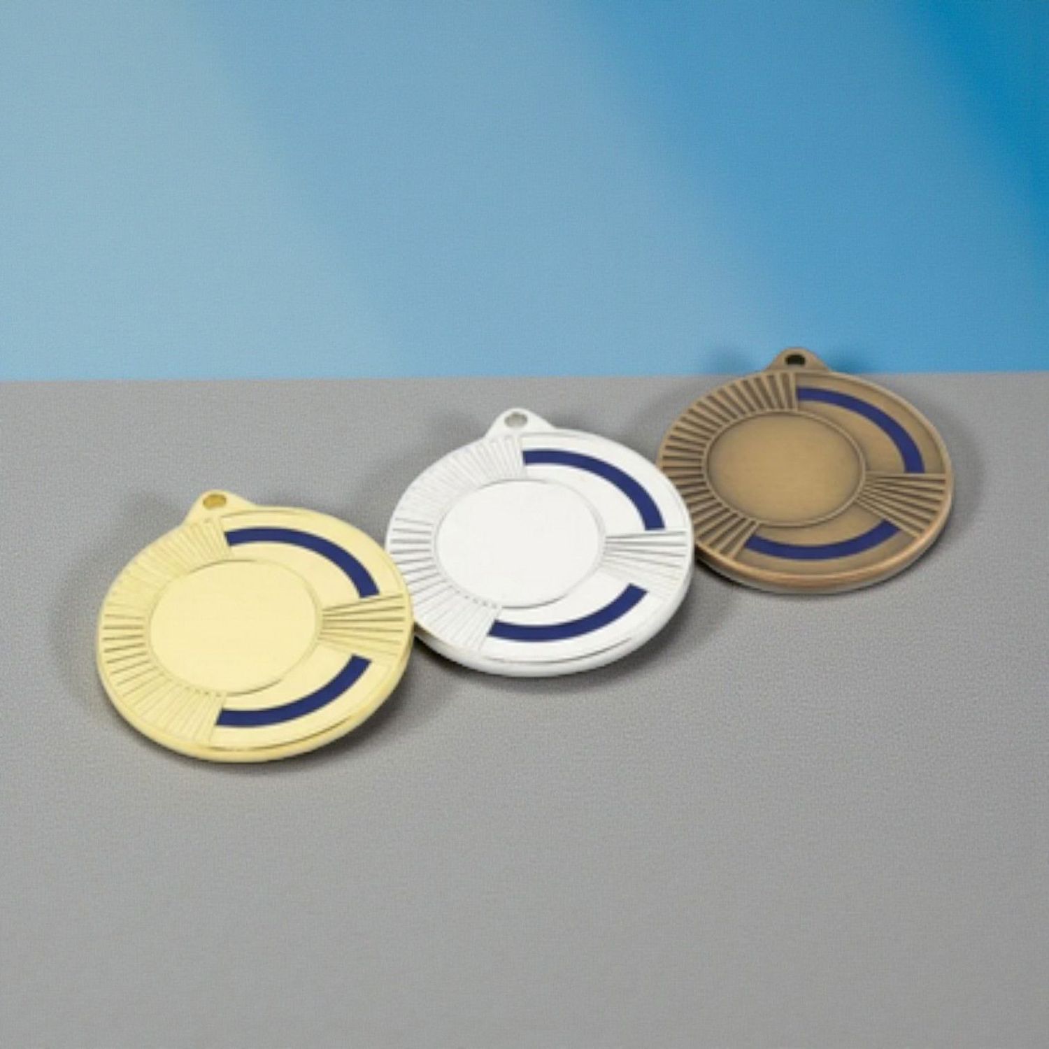 Metallmedaille mit facettiertem Randdesign und farbigem blauen Akzent. Durchmesser Ø 5 cm