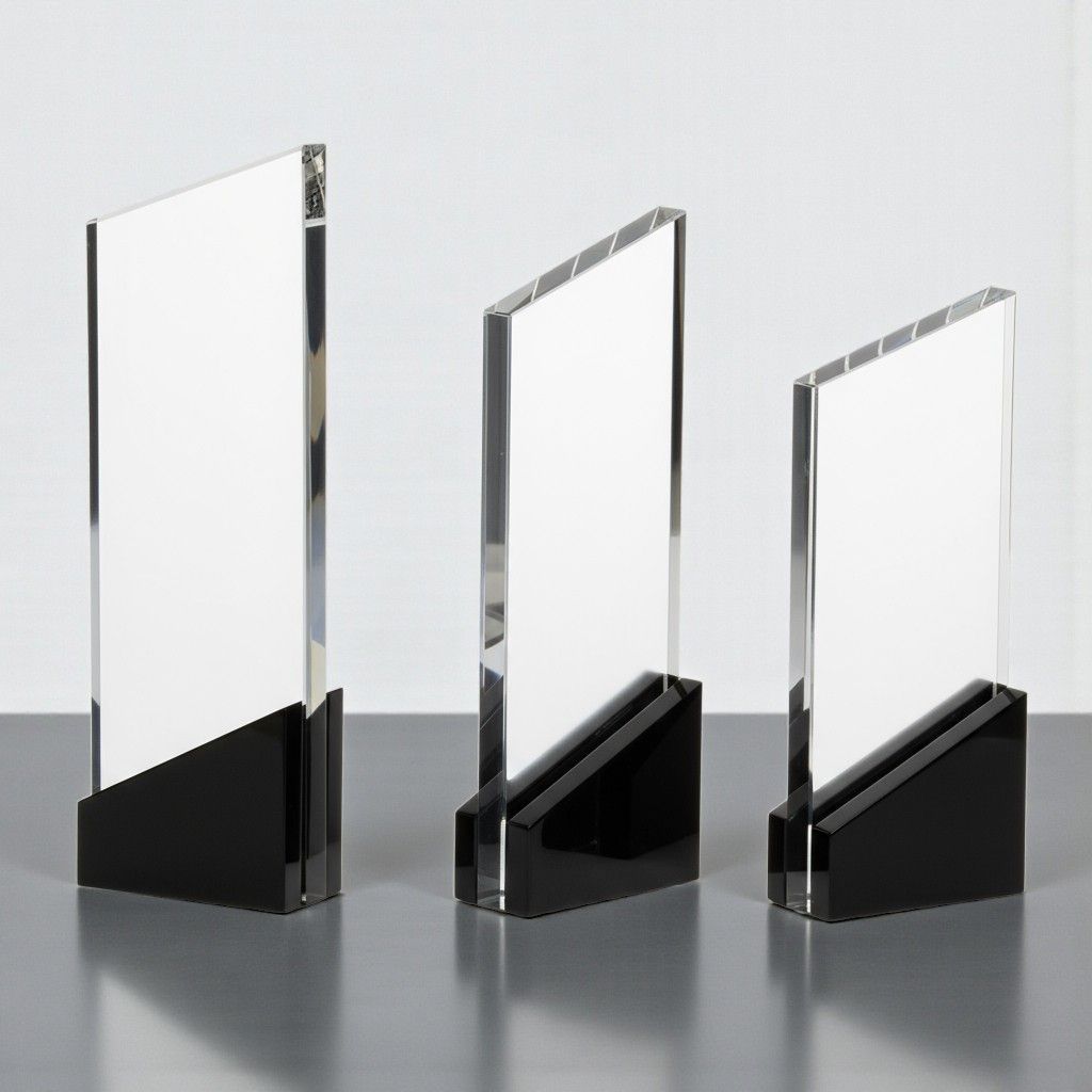 Klare Glastrophäe mit schwarzem Sockel und kantiger Form auf graublauem Hintergrund.