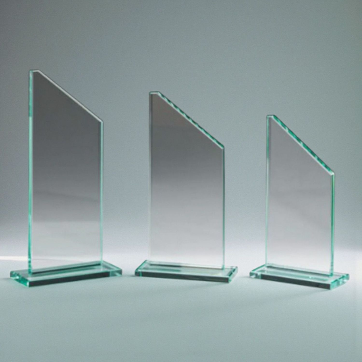 Jadeglas-Trophäe Drei Jadeglas-Trophäen mit schräger Oberkante und klarem Glassockel in unterschiedlichen Höhen, Studioaufnahme.
