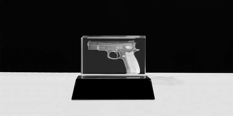 3D Glasblock mit Pistolenmotiv auf schwarzem Sockel