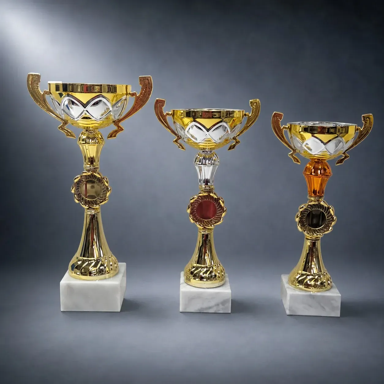 3er Pokalset mit goldenen Metallschalen, Marmorsockeln und Mittelteilen in Gold, Silber und Bronze, inklusive Emblem