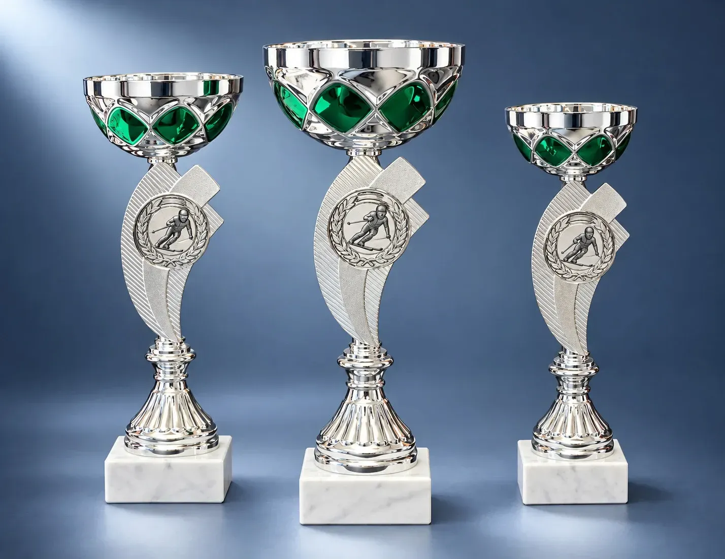 Pokal Drei silberfarbene Pokale mit grünen Metallschalen, geschwungenem Mittelteil mit Emblemträger und weißem Marmorsockel in vers