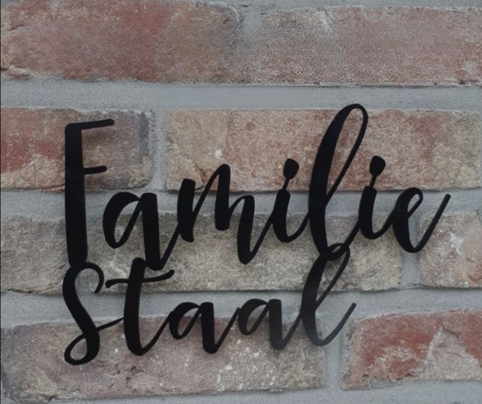 zwart rvs familiebord met sierlijke naam op bakstenen gevel