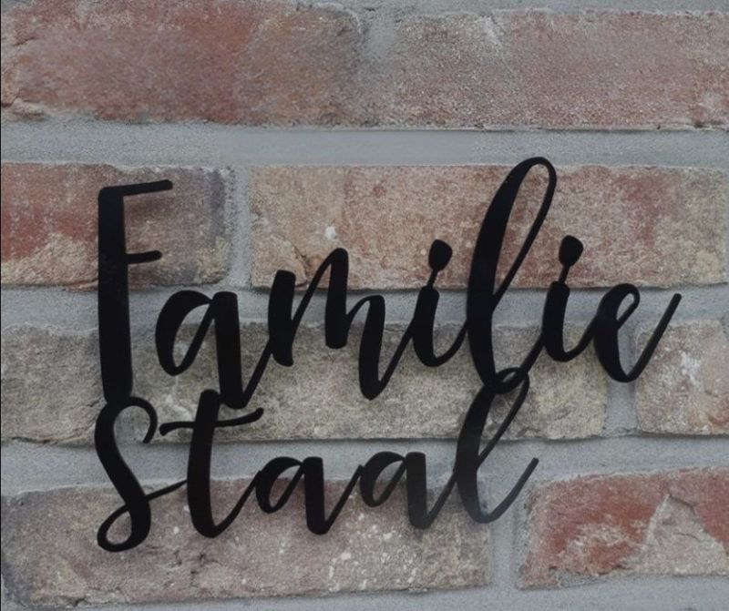 Zwart rvs familiebord met sierlijke naam zwart rvs familiebord met sierlijke naam op bakstenen gevel