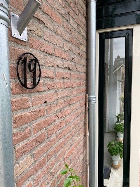 Rond kunststof huisnummer zwart voor buiten Rond zwart kunststof huisnummer gemonteerd op een bakstenen gevel naast de voordeur