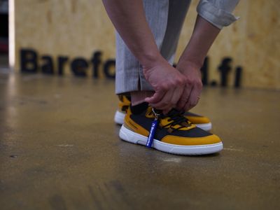 Nainen sovittaa paljasjalkakenkiä barefooted myymälässä Helsingissä