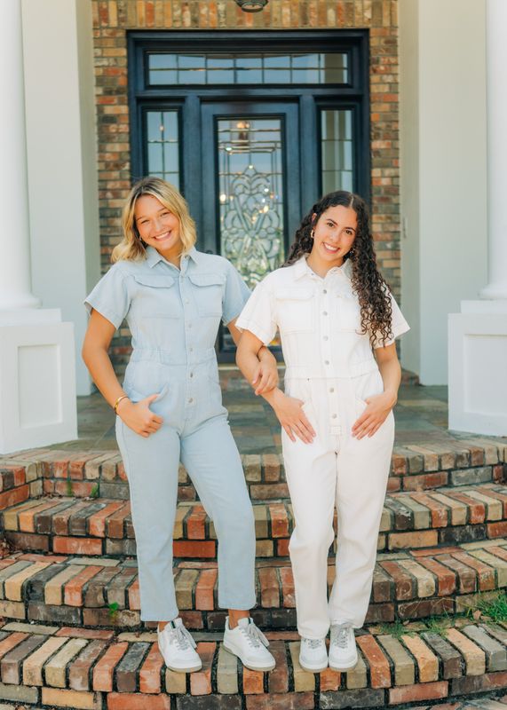 Side-by-side view of models wearing the Denim Utility Jumpsuit in white and light wash, hands in pockets.