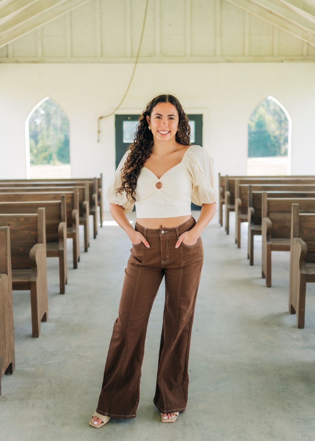 Full-length view of ivory puff sleeve ring-front crop top styled with brown pants.