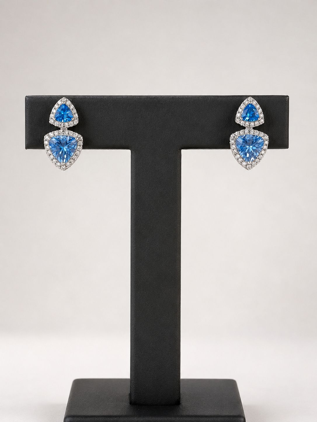 Elegante zilveren oorbellen met aqua-kleur zirkonia, afgewerkt met een rand van kleine heldere steentjes