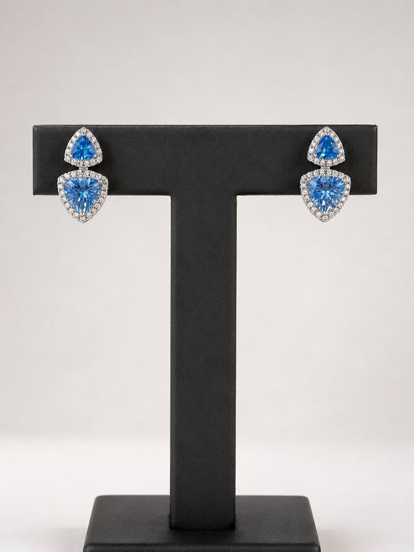 Elegante zilveren oorbellen met aqua-kleur zirkonia, afgewerkt met een rand van kleine heldere steentjes