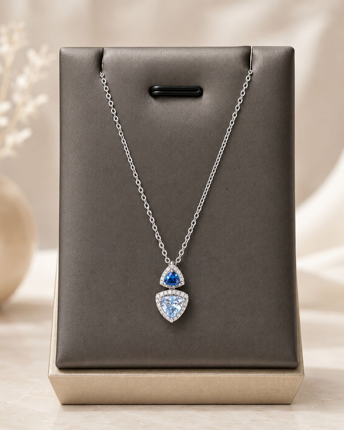 Zilveren ketting met dubbele driehoekige hanger, afgewerkt met donkerblauw, lichtblauw en heldere zirkonia.