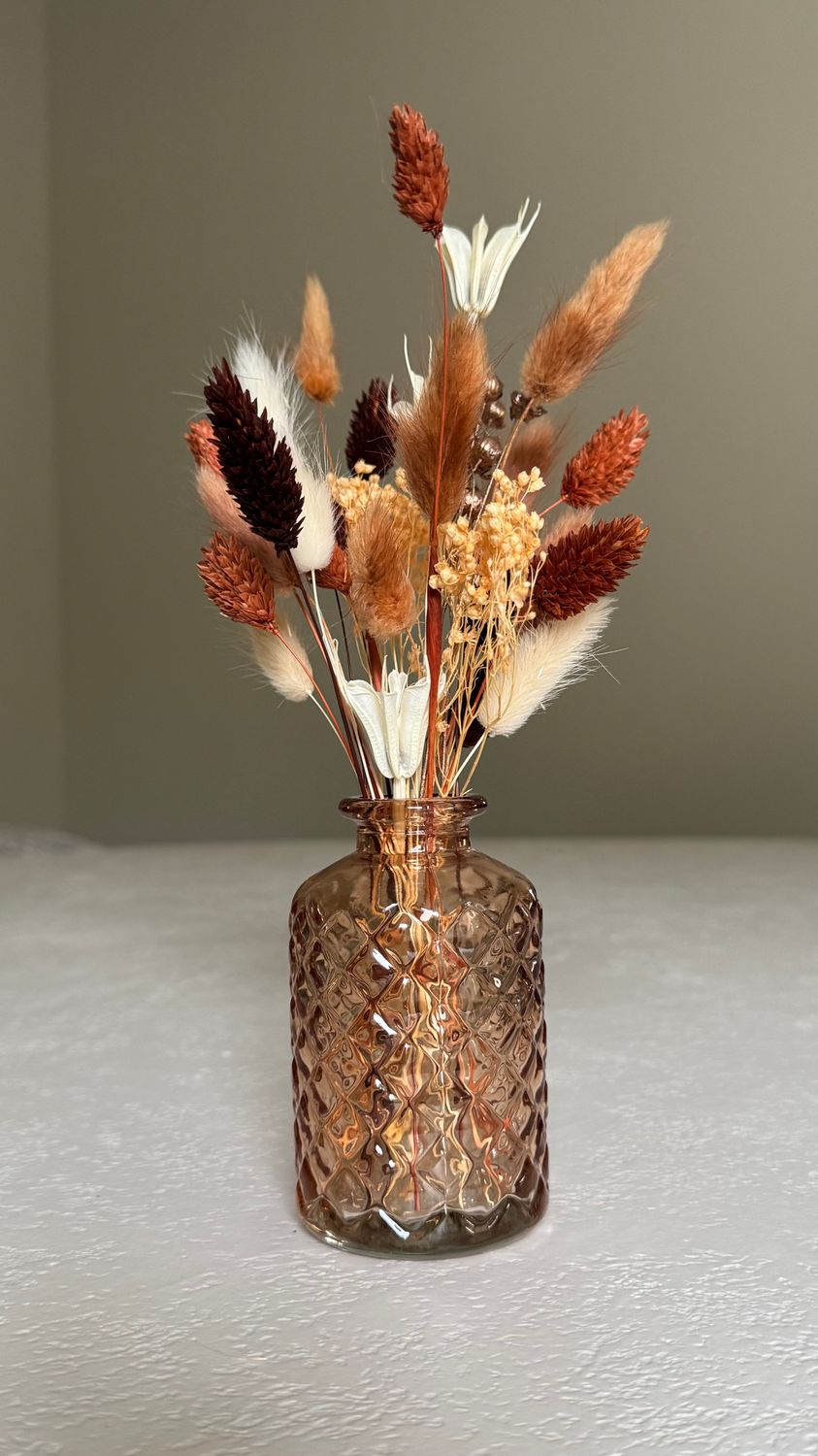 Glazen oranje vaasje met droogbloemen