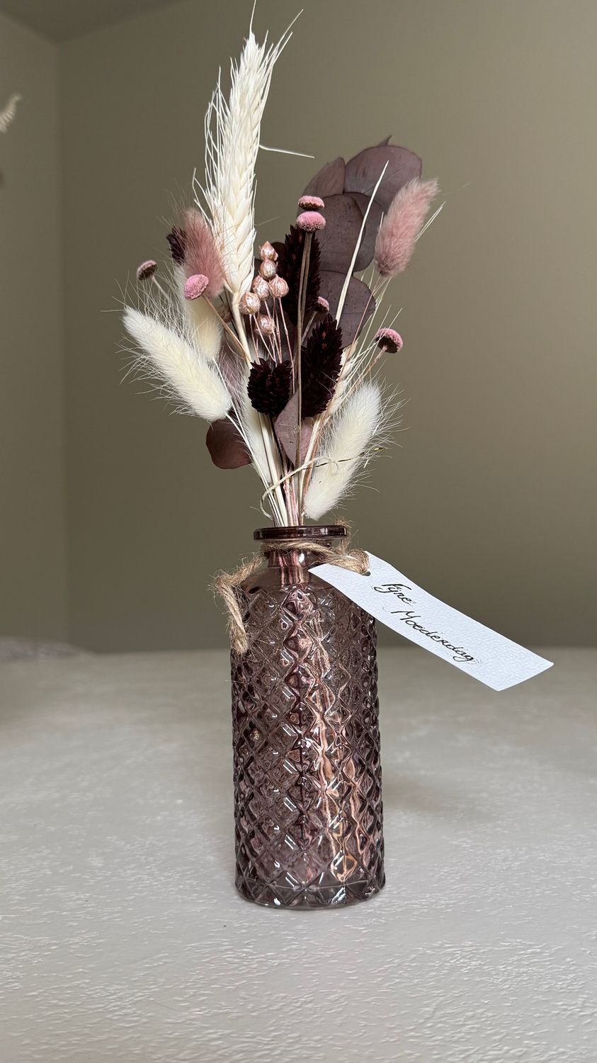 Glazen roze vaasje met droogbloemen