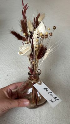 Oranisch glazen vaasje met droogbloemen