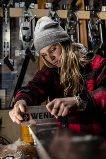 Technician hand-scraping ski wax for smooth base finish and optimal glide performance across varied snow conditions