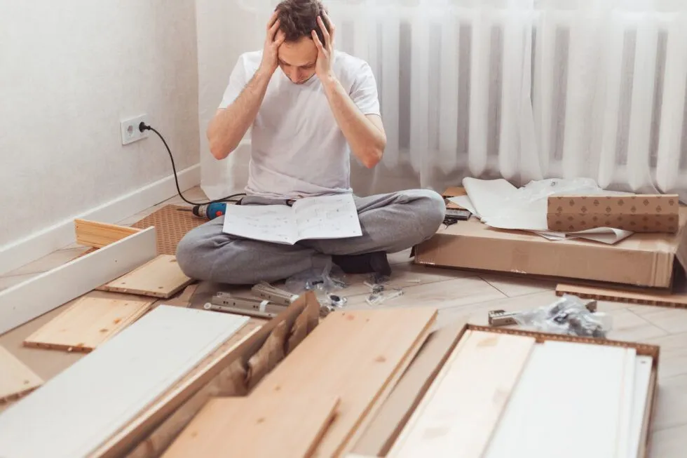 A man is sitting on the floor with his hands on his head.