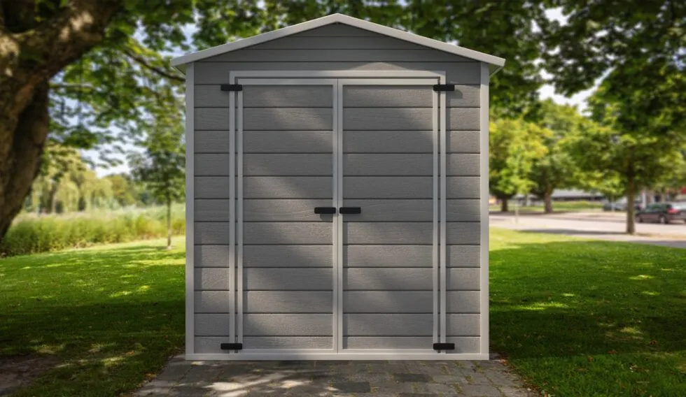 A gray plastic shed is sitting in the middle of a lush green field.