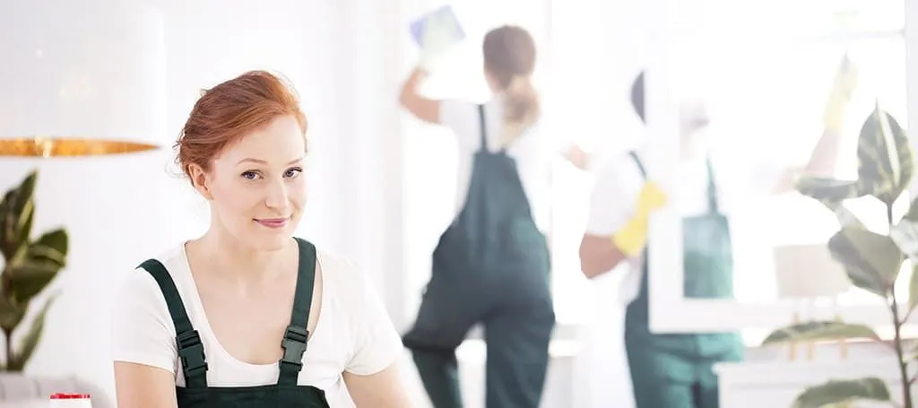 A woman in overalls is standing in front of a group of cleaners.