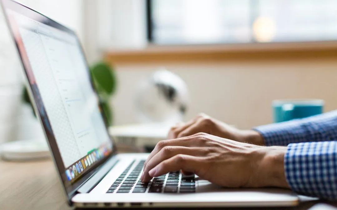 A person is typing on a laptop computer.