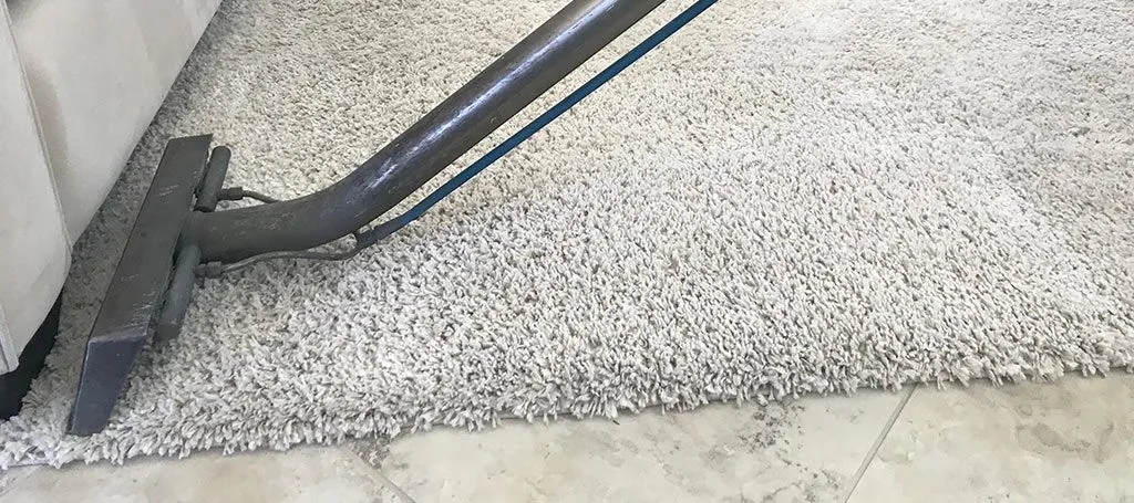 A vacuum cleaner is cleaning a carpet in a living room.