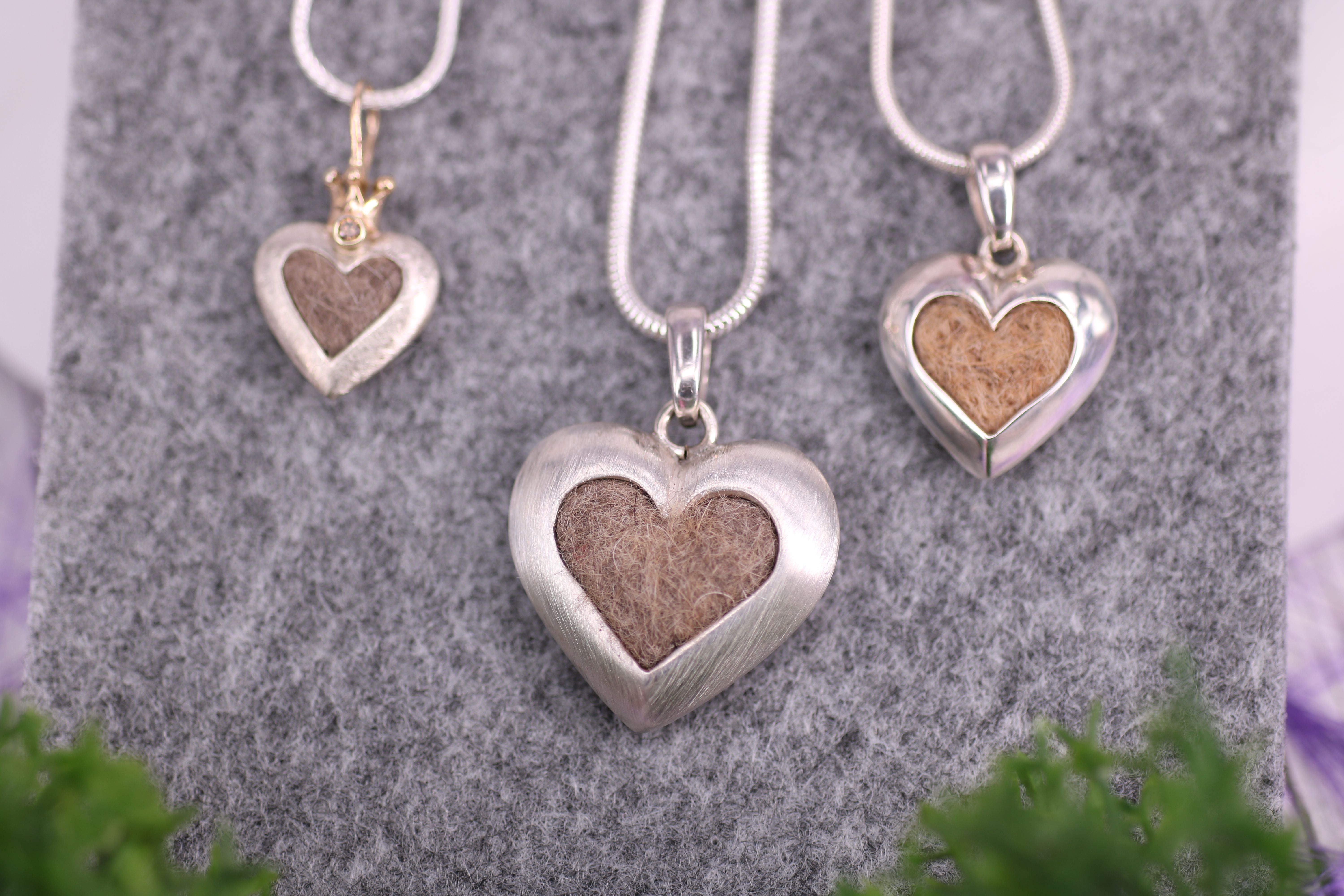 drei verschiedene Modelle symmetrischer Herzen mit eingefassten Tierhaaren. Handgefertigter Schmuck aus Sterlingsilber