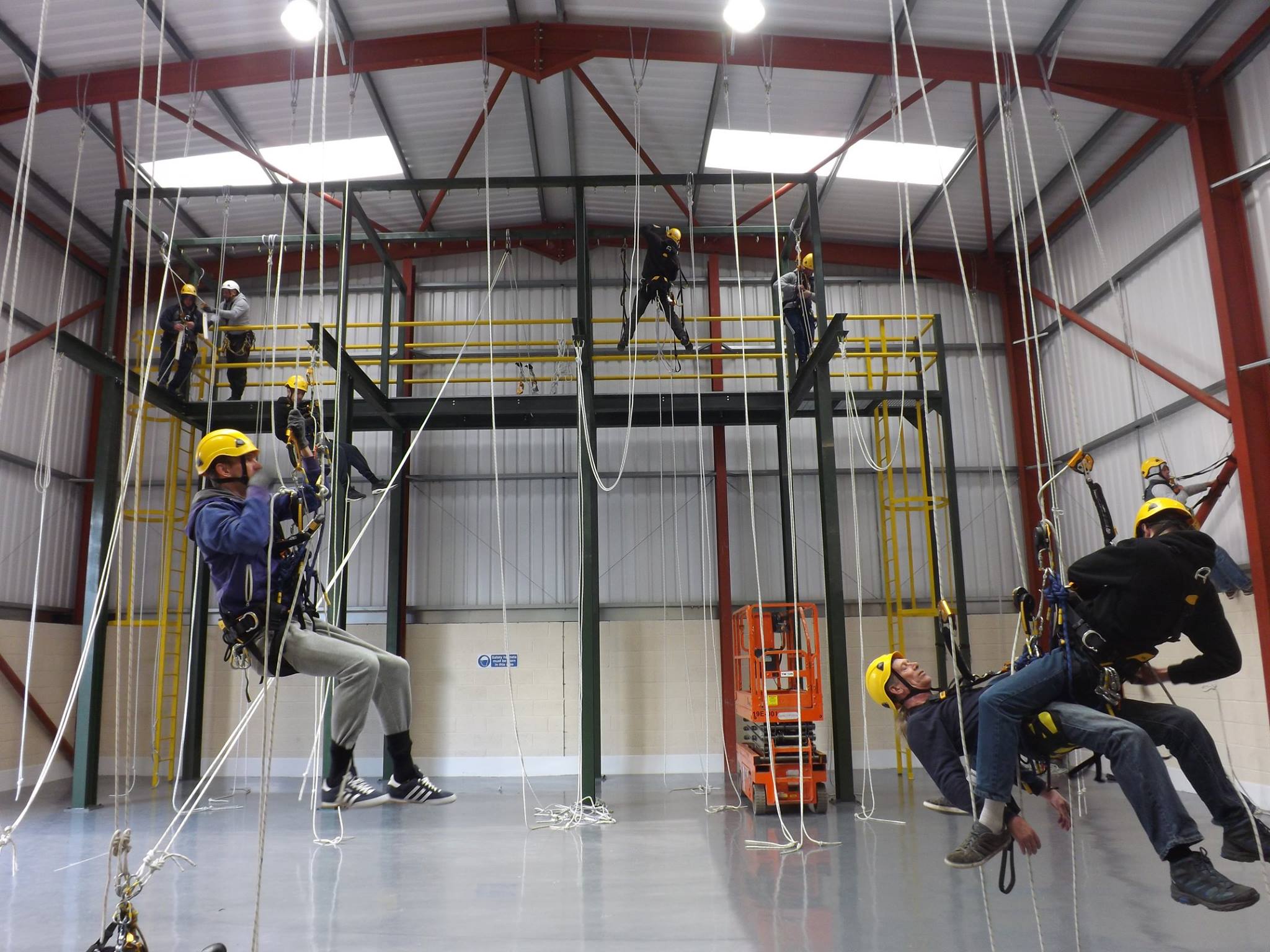 men are practicing their abseiling on a rope access course in a training centre