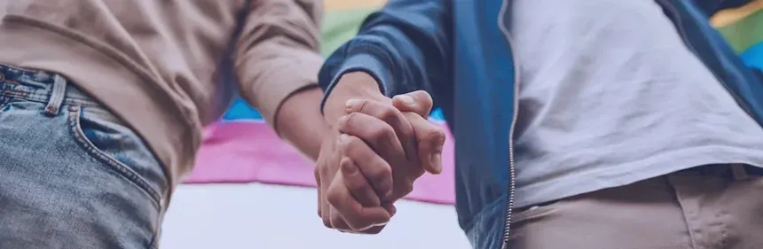 Liebe ist Liebe im Pride Shop Deutschland, Männer halten Händchen vor einer Regenbogenflagge
